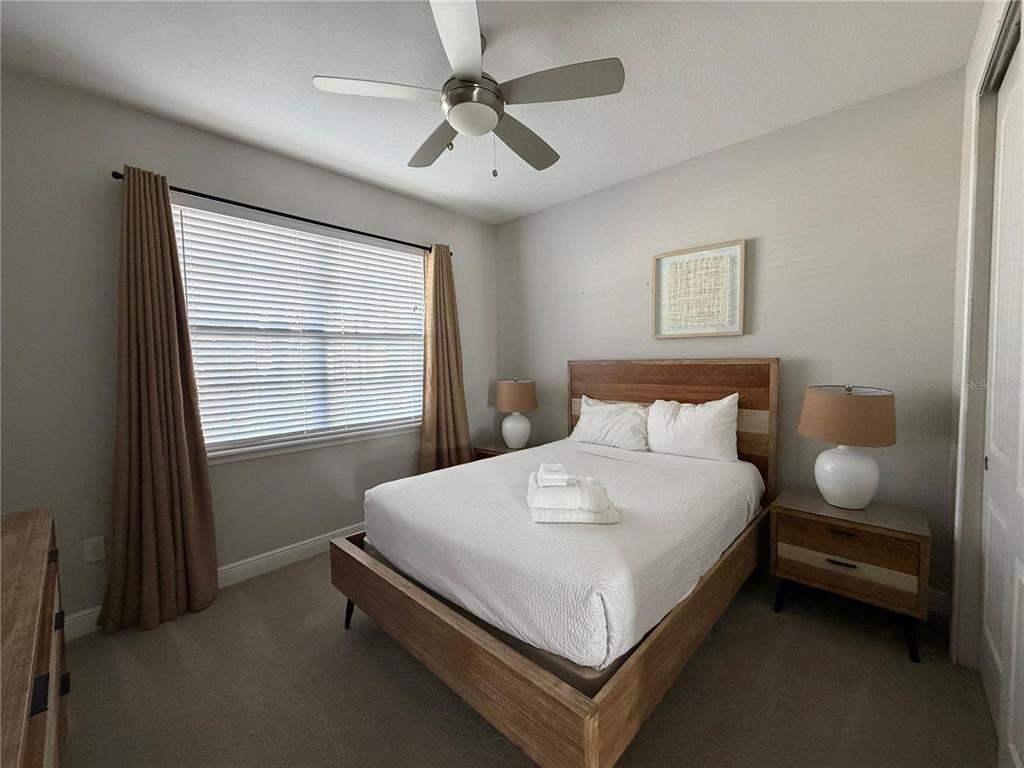 A bedroom features a wooden bed frame, two nightstands, and a ceiling fan — 7676 FAIRFAX DRIVE, KISSIMMEE, FL