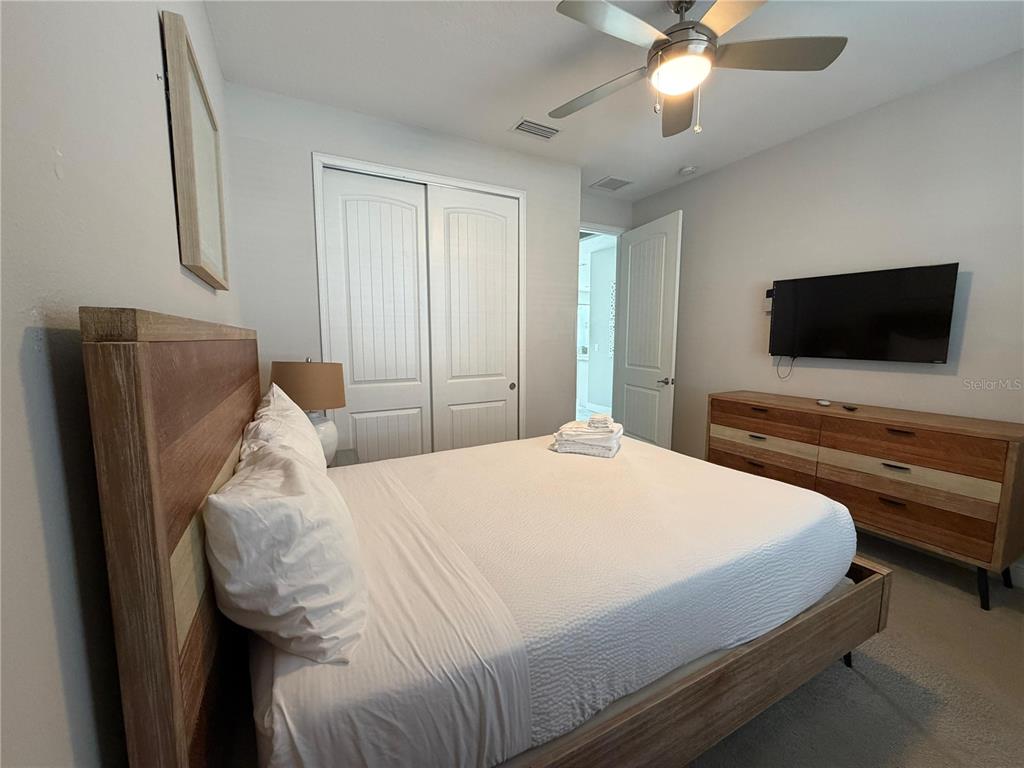 A bedroom features a wooden bed frame, a matching dresser, and a ceiling fan — 7676 FAIRFAX DRIVE, KISSIMMEE, FL