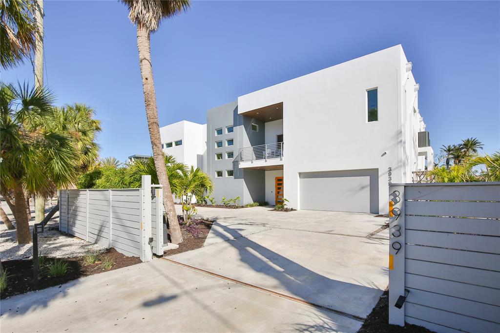 A modern two-story white house with a concrete driveway and a gated entrance — 3939 HIGEL AVENUE, SARASOTA, FL