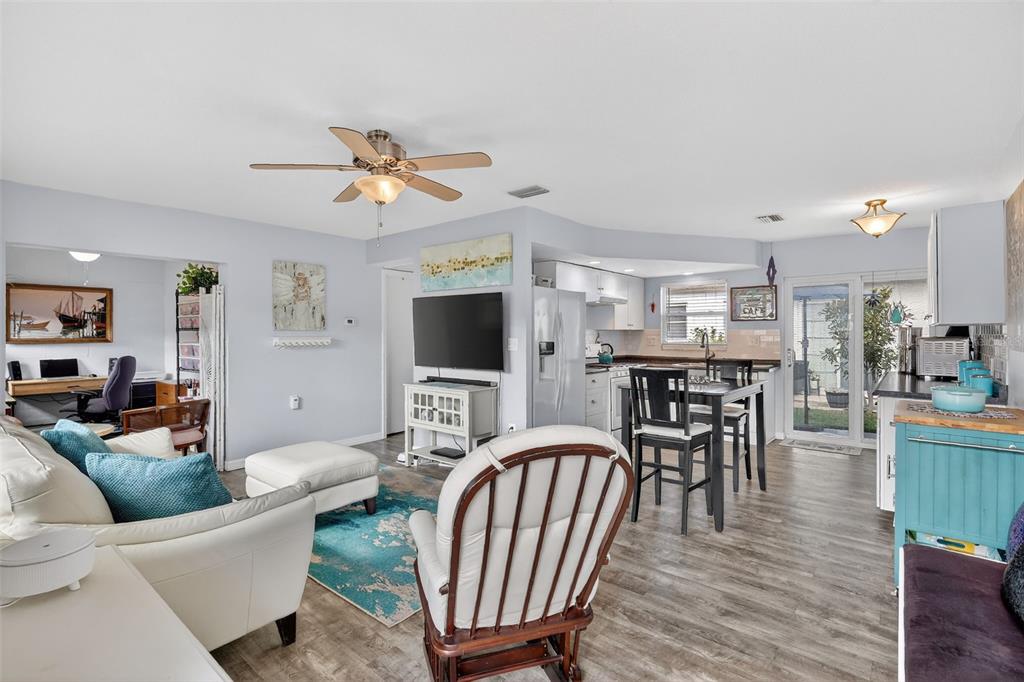 An open-concept living room and kitchen area with light walls and wood-look flooring — 7825 38TH TERRACE N UNIT 7825, ST PETERSBURG, FL