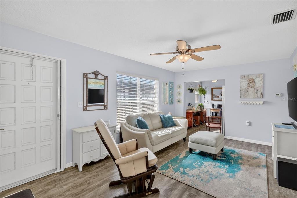A living room features a white sofa, a rocking chair, and a blue area rug — 7825 38TH TERRACE N UNIT 7825, ST PETERSBURG, FL