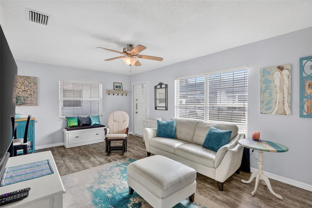 A living room features a white sofa, ottoman, rocking chair, and a window bench seat — 7825 38TH TERRACE N UNIT 7825, ST PETERSBURG, FL