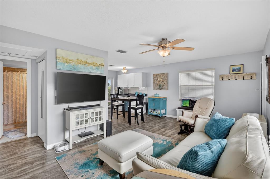 A living room and dining area feature light gray walls, wood-look flooring, and a ceiling fan — 7825 38TH TERRACE N UNIT 7825, ST PETERSBURG, FL