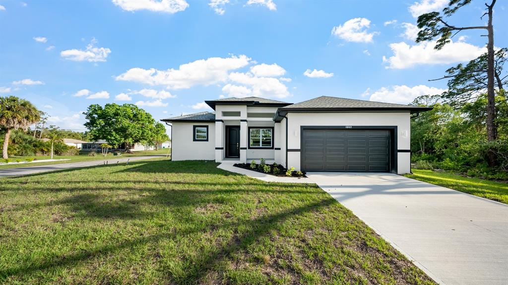 A modern, single-story house with a white exterior, dark trim, and a two-car garage — 18265 LAKE WORTH BOULEVARD, PORT CHARLOTTE, FL
