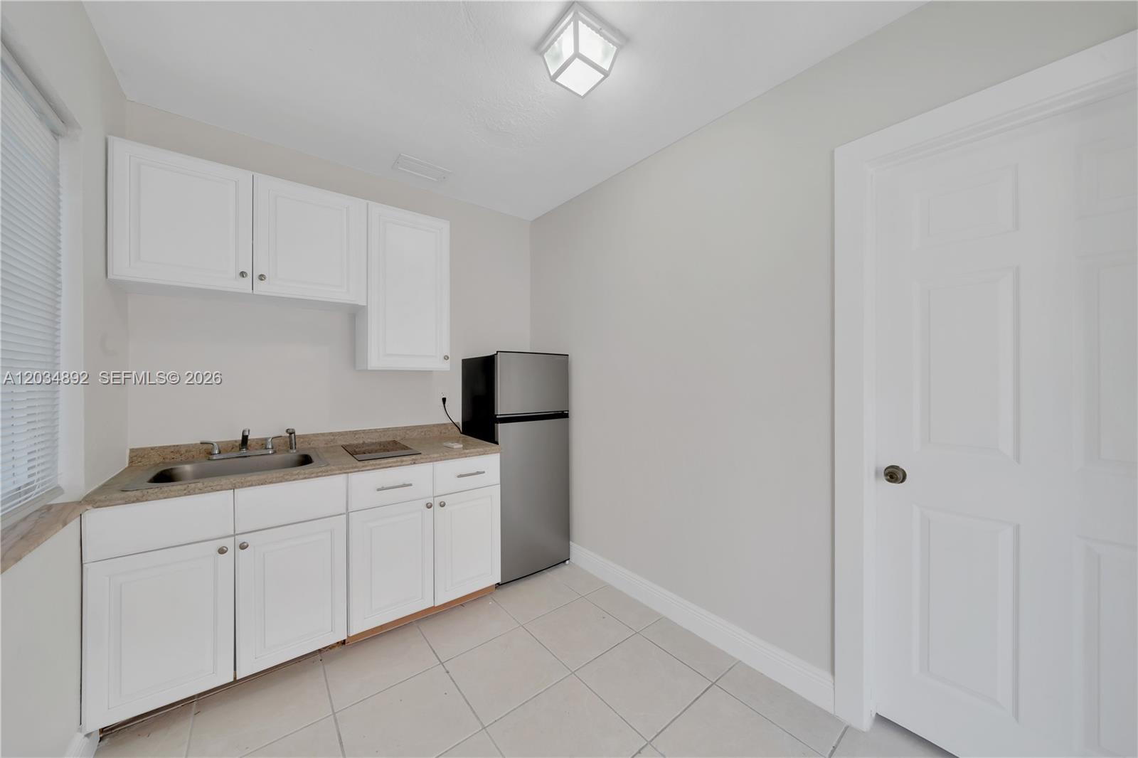 A small kitchenette features white cabinets, a stainless steel refrigerator, and a sink — 7555 SW 28th St Rd # b, Miami FL 33155, MIAMI, FL