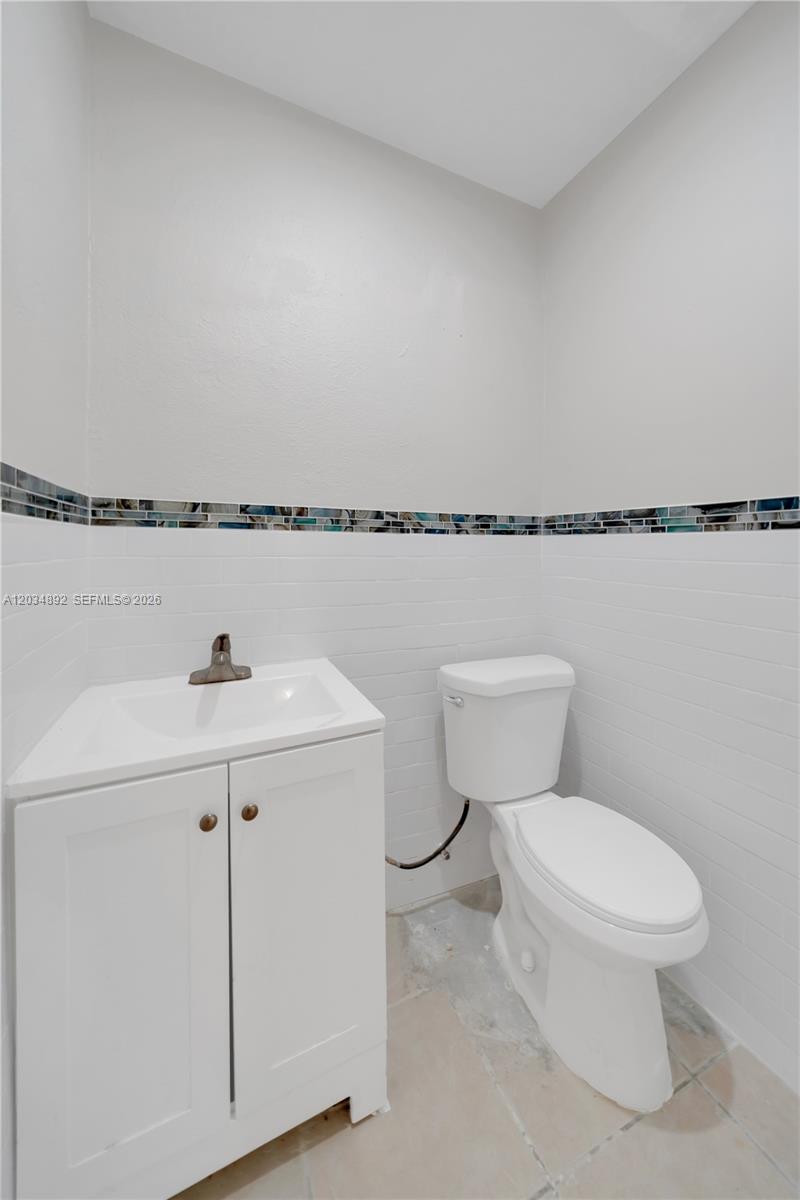 A small bathroom features a white vanity, a toilet, and a decorative blue mosaic tile border — 7555 SW 28th St Rd # b, Miami FL 33155, MIAMI, FL