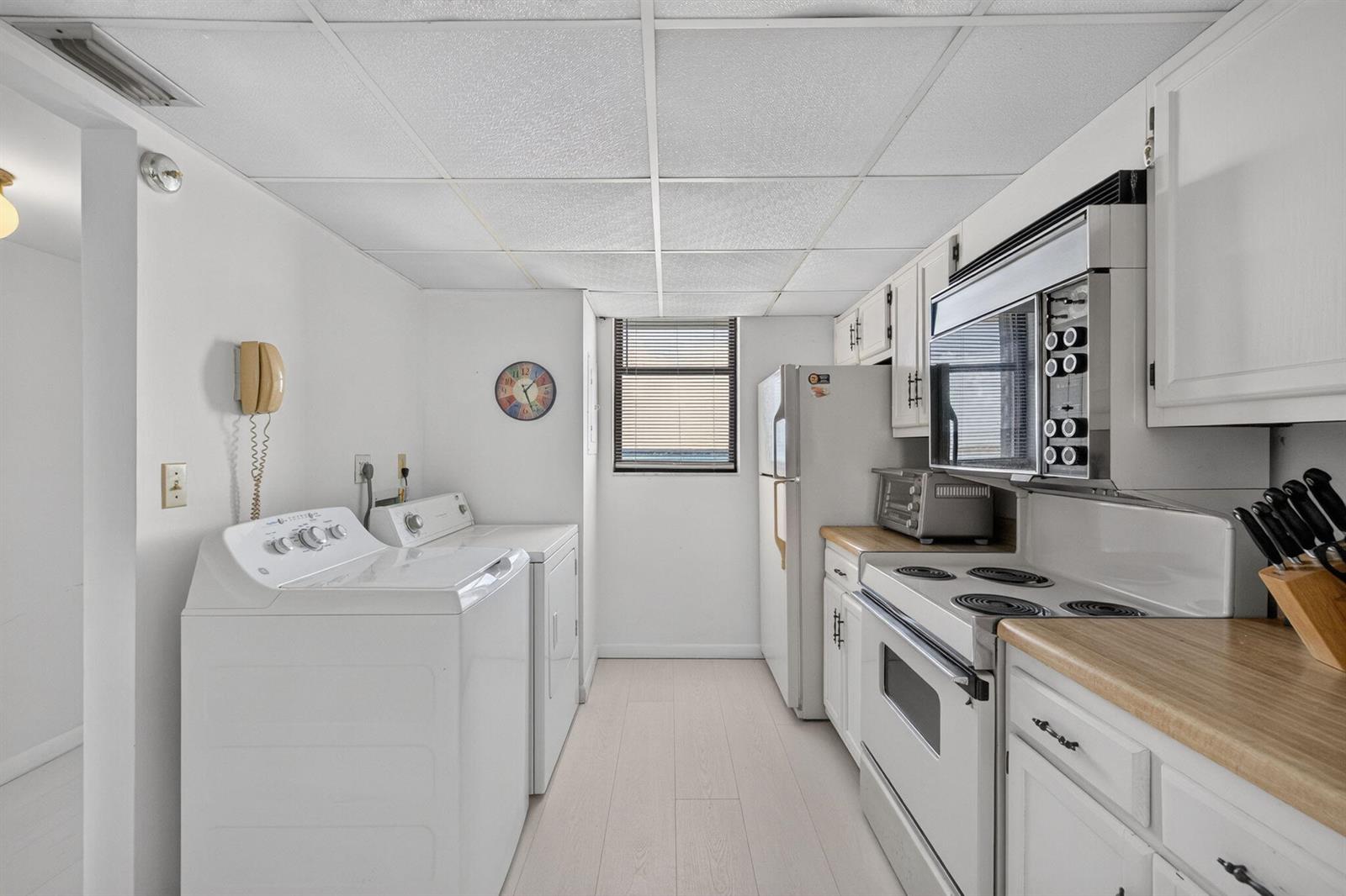 A kitchen and laundry room combination features white appliances, white cabinetry, and light wood countertops — 9900 S Ocean Drive # 1505, Jensen Beach FL 34957, JENSEN BEACH, FL