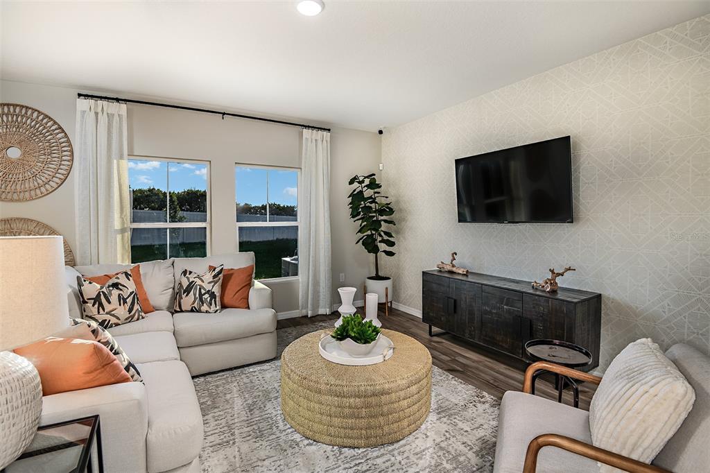 A living room features a sectional sofa, a round ottoman, and a wall-mounted television — 4337 RIVERBEND BOULEVARD, HAINES CITY, FL