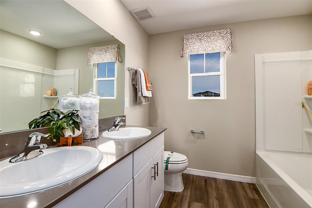 A bathroom features a double vanity with white cabinets, a mirror, and a shower-tub combination — 4337 RIVERBEND BOULEVARD, HAINES CITY, FL