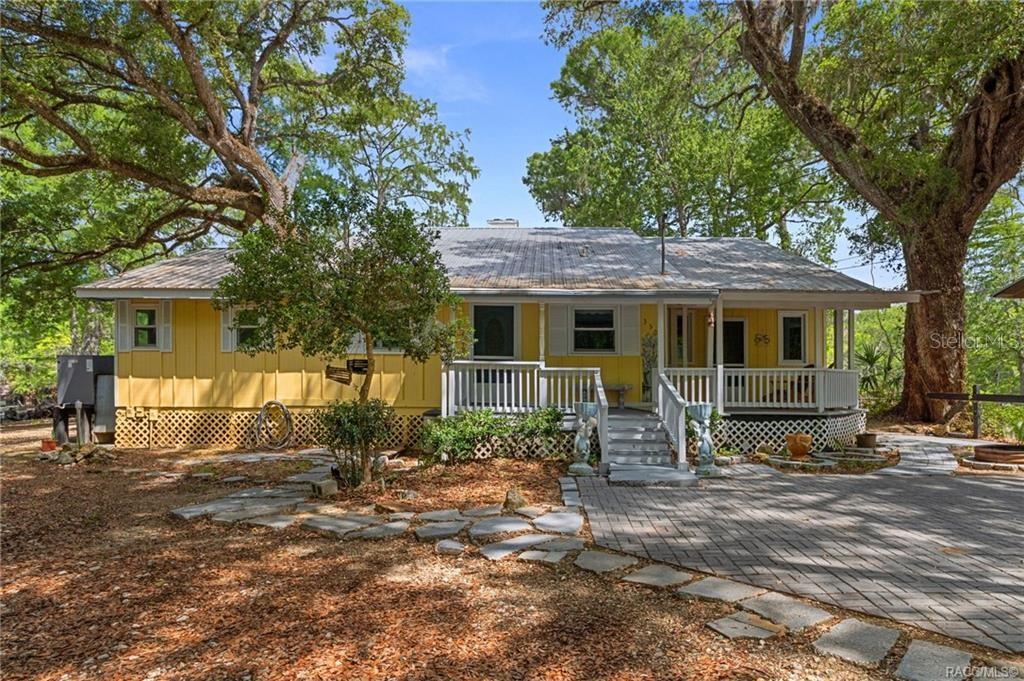 A yellow, single-story house with a metal roof, front porch, and stone paver driveway — 3503 E WESTCOVE COURT, DUNNELLON, FL