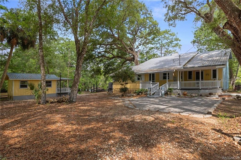 A yellow house with a metal roof and a detached shed sit in a wooded yard — 3503 E WESTCOVE COURT, DUNNELLON, FL