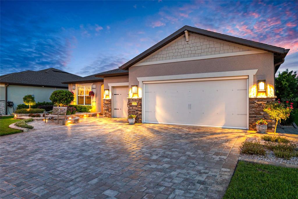 A single-story house exterior features a stone-accented facade, a paved driveway, and a garage — 8690 SW 61ST LOOP, OCALA, FL