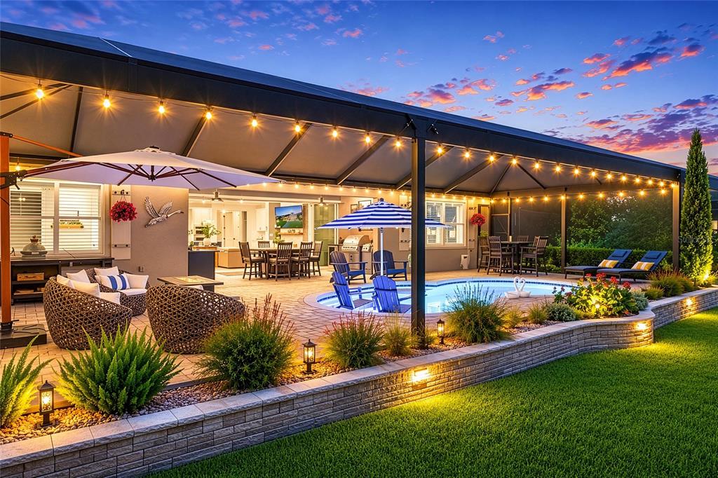 A backyard swimming pool with a screened enclosure, stone retaining wall, and outdoor seating area — 8690 SW 61ST LOOP, OCALA, FL