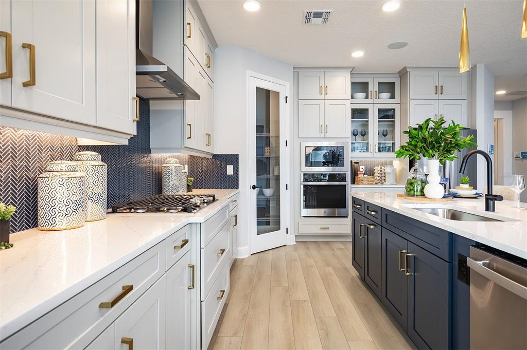 A modern kitchen features light gray cabinets, a navy blue island, and a herringbone backsplash — 842 CREEPING FIG STREET, APOPKA, FL