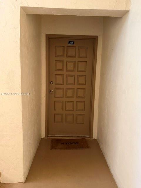 A brown apartment door numbered 205 is set in a recessed entryway with a welcome mat — 7715 SW 86th St # 205, Miami FL 33143, MIAMI, FL