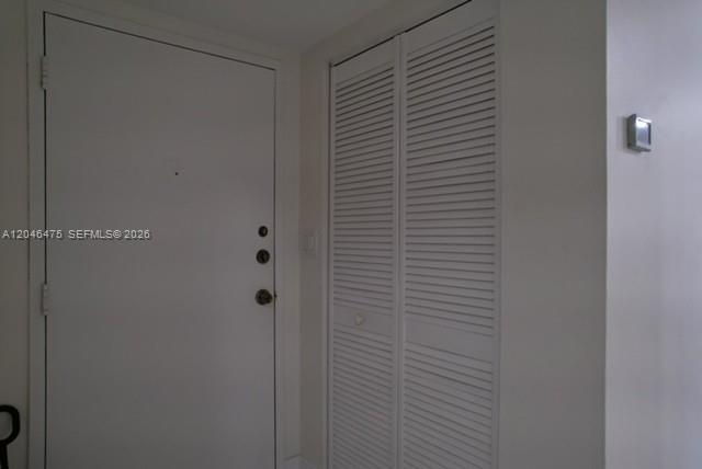 A white entry door sits next to a white louvered closet door in a hallway — 7715 SW 86th St # 205, Miami FL 33143, MIAMI, FL