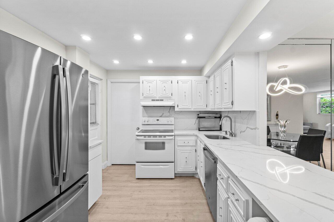 A kitchen with white cabinets, stainless steel appliances, and a white marble-patterned countertop — 6461 NW 2nd Avenue # 411, Boca Raton FL 33487, BOCA RATON, FL
