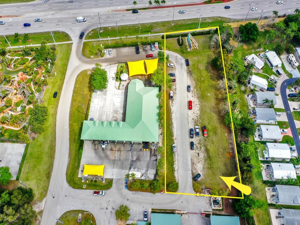 An aerial view shows a commercial property with a green-roofed building and an adjacent vacant lot — S TAMIAMI TRAIL, BONITA SPRINGS, FL