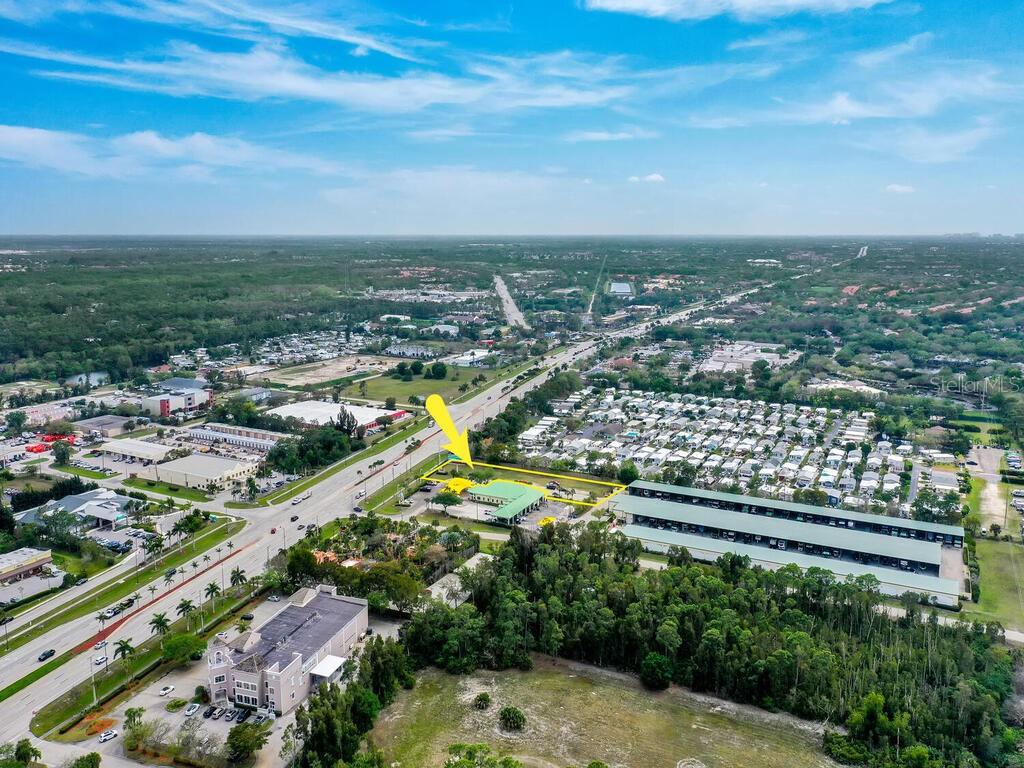 An aerial view shows a commercial building highlighted by a yellow outline near a highway — S TAMIAMI TRAIL, BONITA SPRINGS, FL