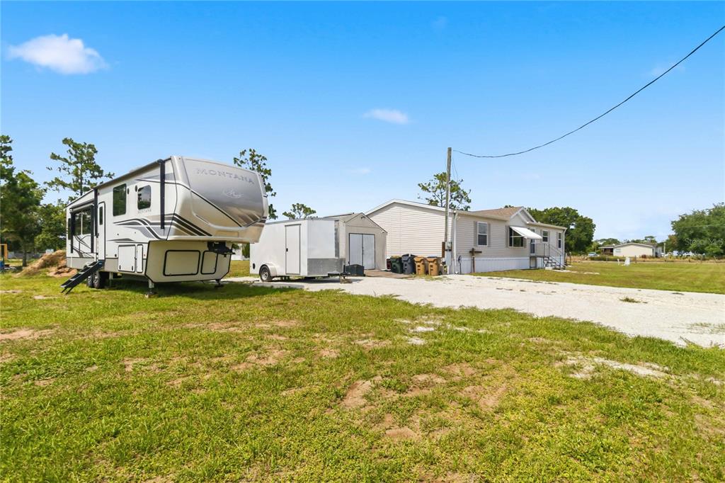 A Montana fifth-wheel trailer, a utility trailer, and a mobile home sit on a lot — 9109 ATLAS DRIVE, ST CLOUD, FL