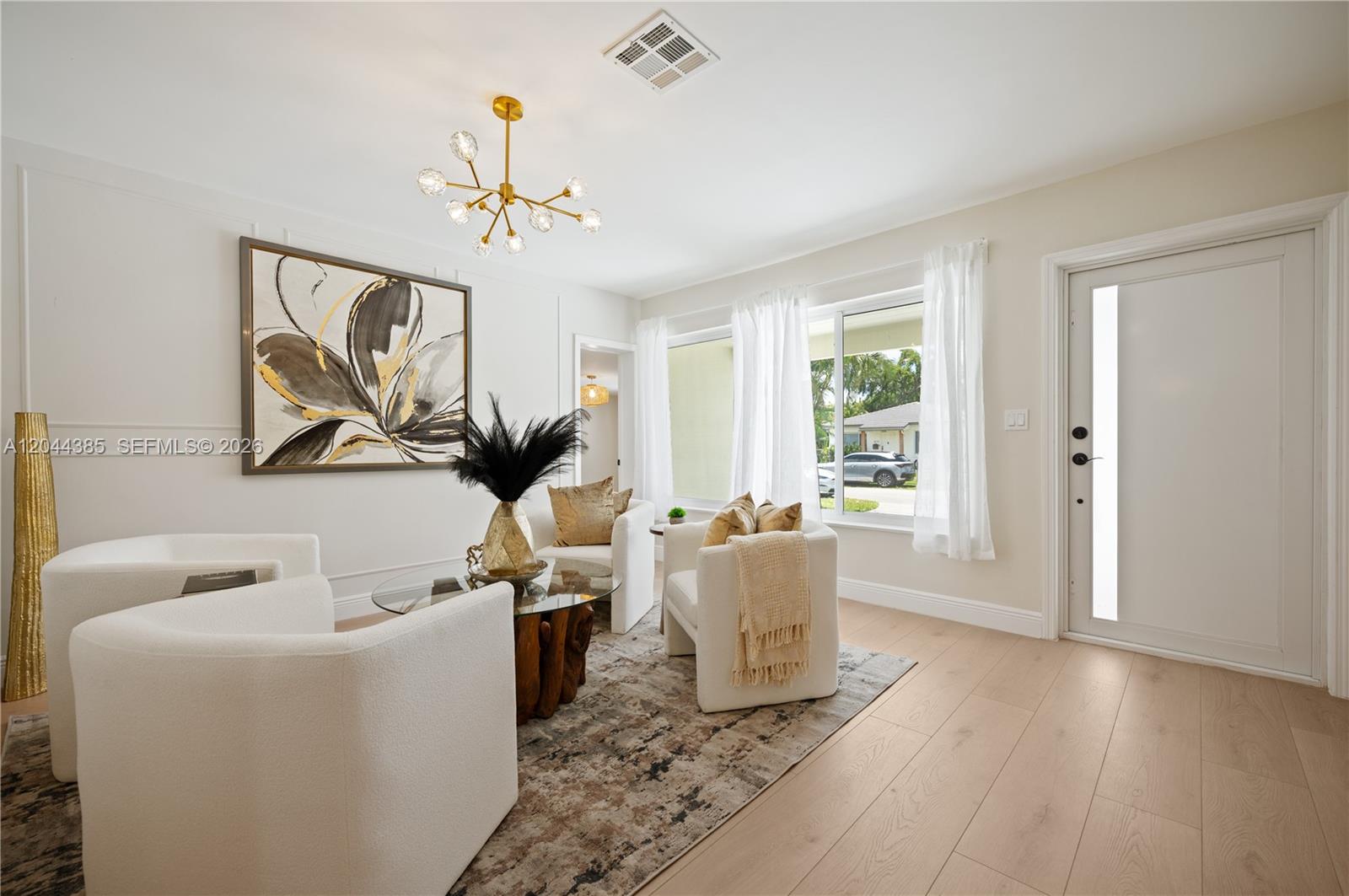 A bright living room features white armchairs, a glass coffee table, and a modern chandelier — 4220 SW 14th St # 4220, Miami FL 33134, MIAMI, FL