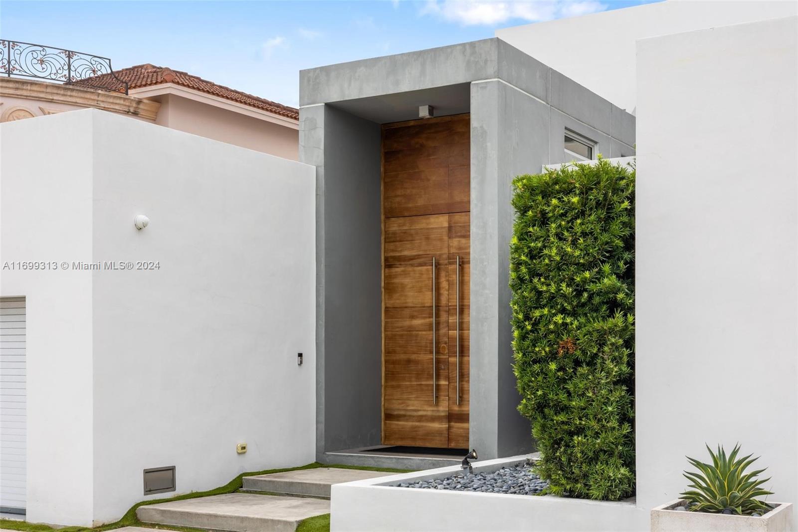 A modern home entrance features a tall wooden door set within a grey concrete frame — 323 Atlantic Ave, Sunny Isles Beach FL 33160, SUNNY ISLES BEACH, FL