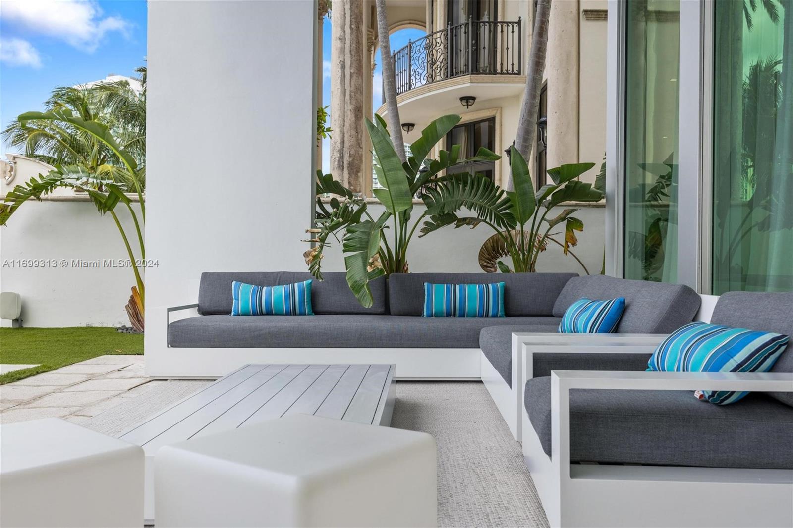 An outdoor patio features a modern gray sectional sofa with blue striped pillows and furniture — 323 Atlantic Ave, Sunny Isles Beach FL 33160, SUNNY ISLES BEACH, FL
