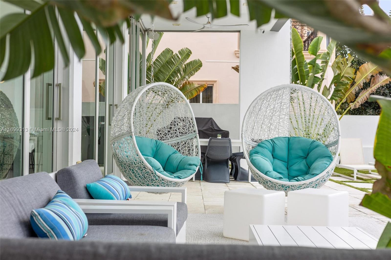 A patio features two white hanging egg chairs with teal cushions and gray lounge seating — 323 Atlantic Ave, Sunny Isles Beach FL 33160, SUNNY ISLES BEACH, FL