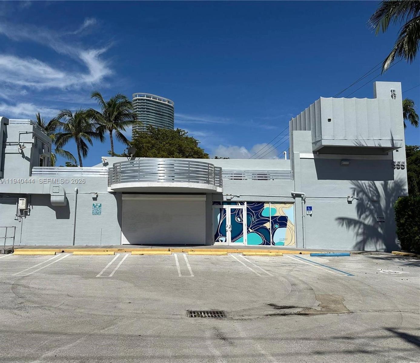A light gray commercial building features a roll-up door, glass entrance, and a parking lot — 555 Jefferson Ave, Miami Beach FL 33139, MIAMI BEACH, FL