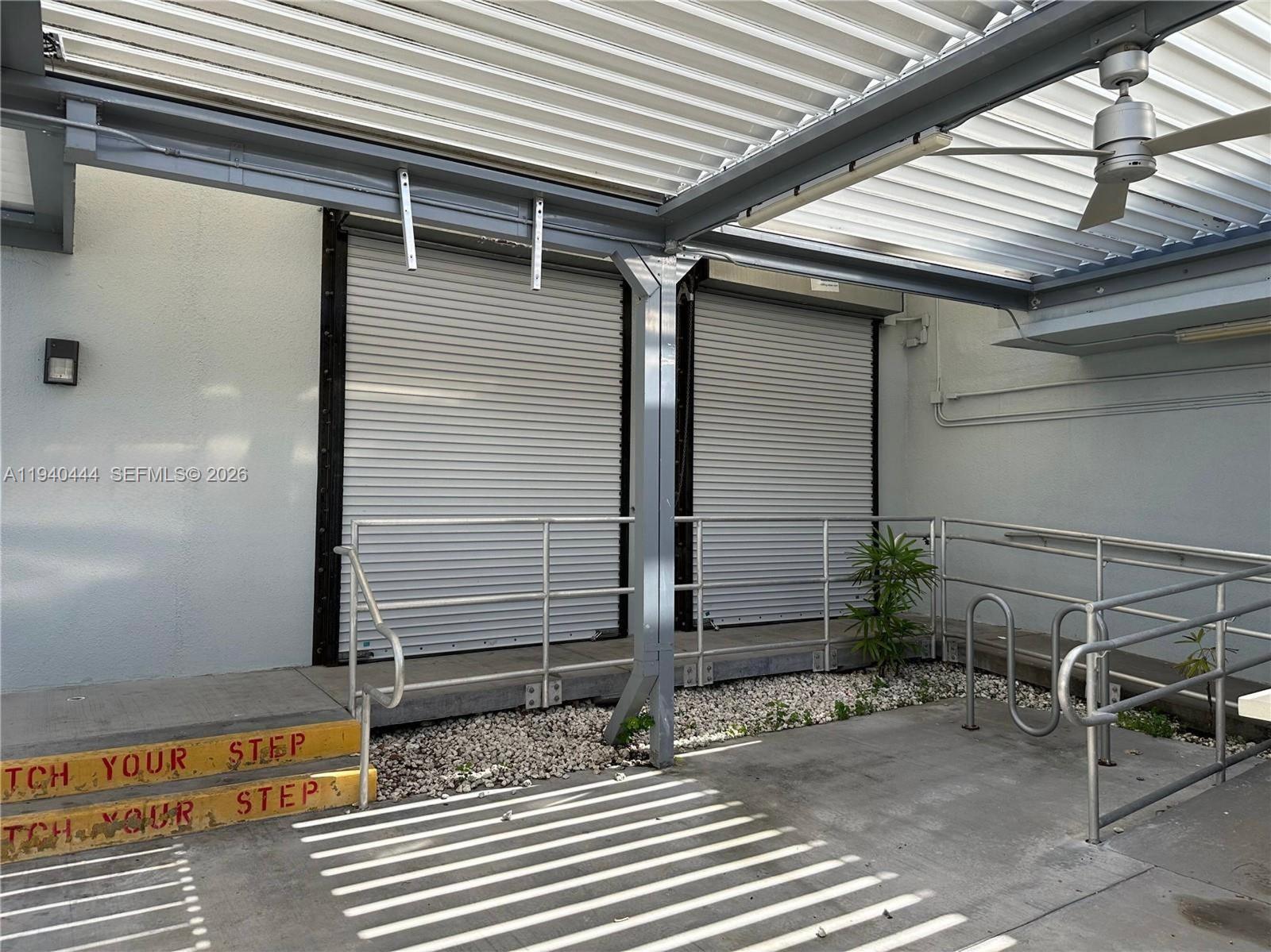 A covered outdoor area features two roll-up doors, metal railings, and concrete steps — 555 Jefferson Ave, Miami Beach FL 33139, MIAMI BEACH, FL