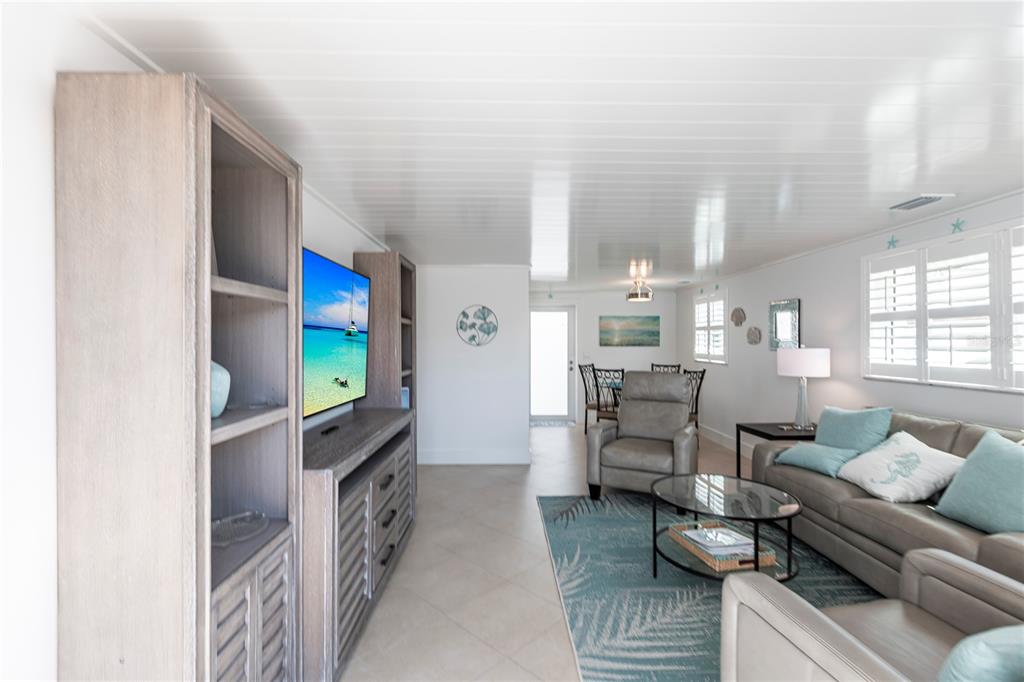 A living room features light-colored tile floors, a gray sofa, and a television console — 6154 MIDNIGHT PASS ROAD UNIT A1, SARASOTA, FL