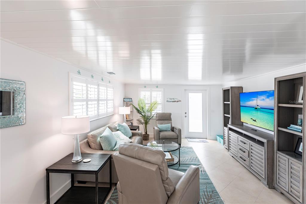 A living room features a sofa, two recliners, a television console, and white plank ceilings — 6154 MIDNIGHT PASS ROAD UNIT A1, SARASOTA, FL