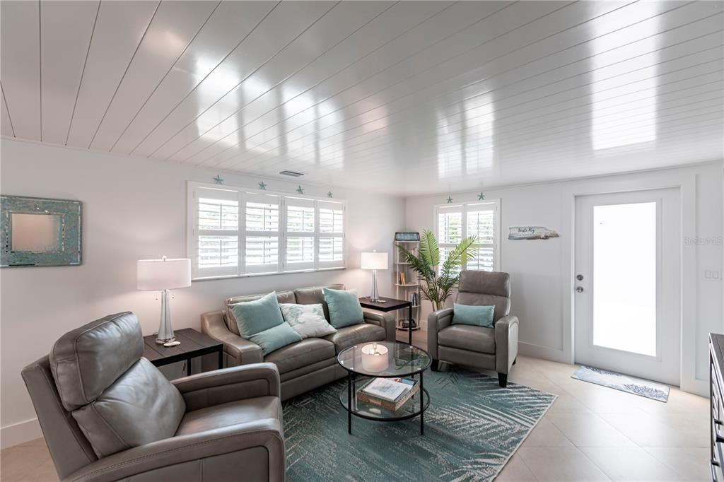 A living room features grey leather furniture, a glass coffee table, and a white ceiling — 6154 MIDNIGHT PASS ROAD UNIT A1, SARASOTA, FL