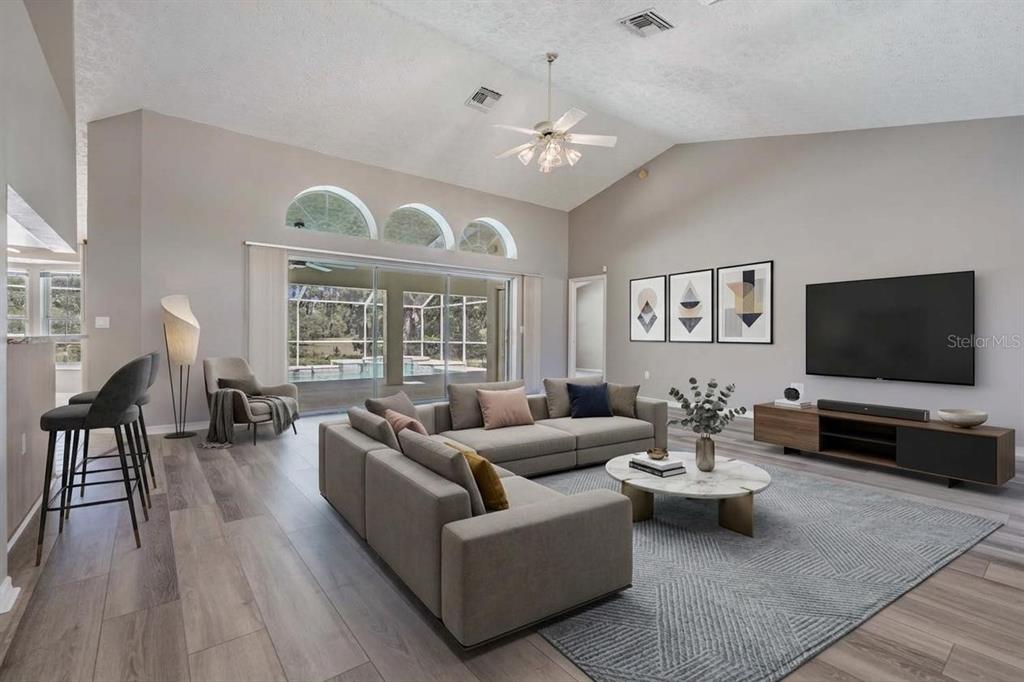 A spacious living room features a sectional sofa, a television, and large sliding glass doors — 1091 TOURNAMENT DRIVE, SPRING HILL, FL