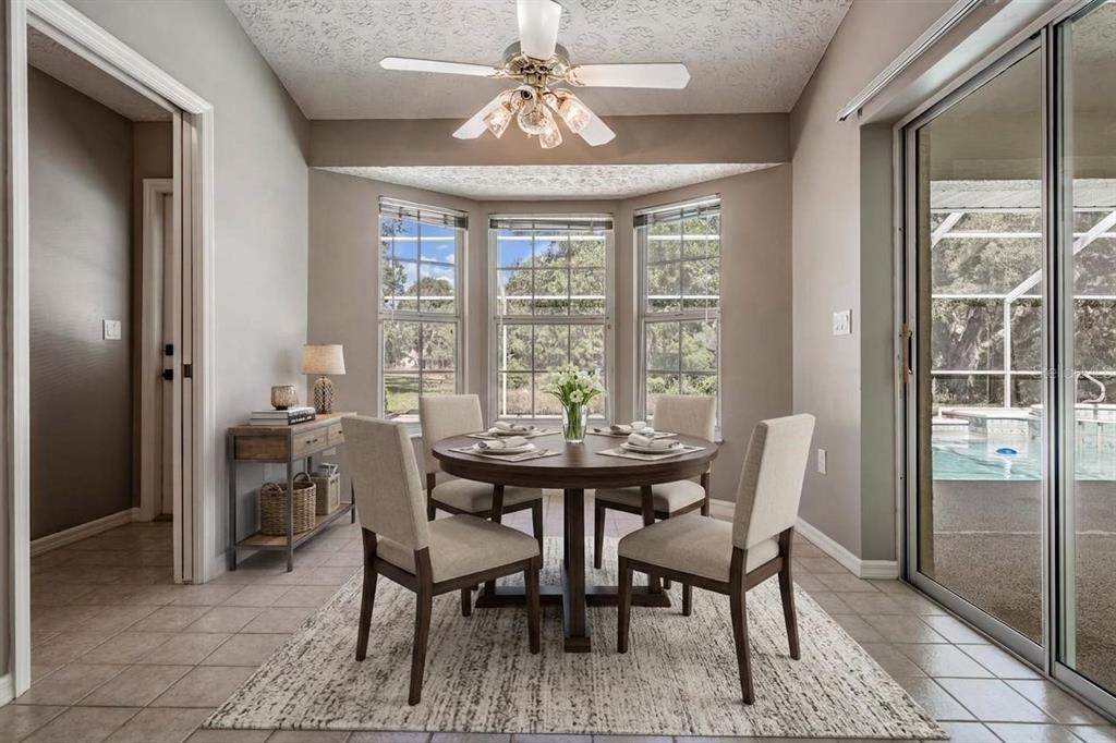 A dining area with a round table, four chairs, a ceiling fan, and sliding glass doors — 1091 TOURNAMENT DRIVE, SPRING HILL, FL