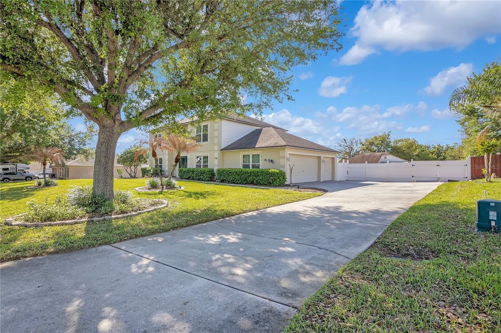 A two-story house with a concrete driveway, a large tree, and a white fence — 16012 HORIZON COURT, CLERMONT, FL