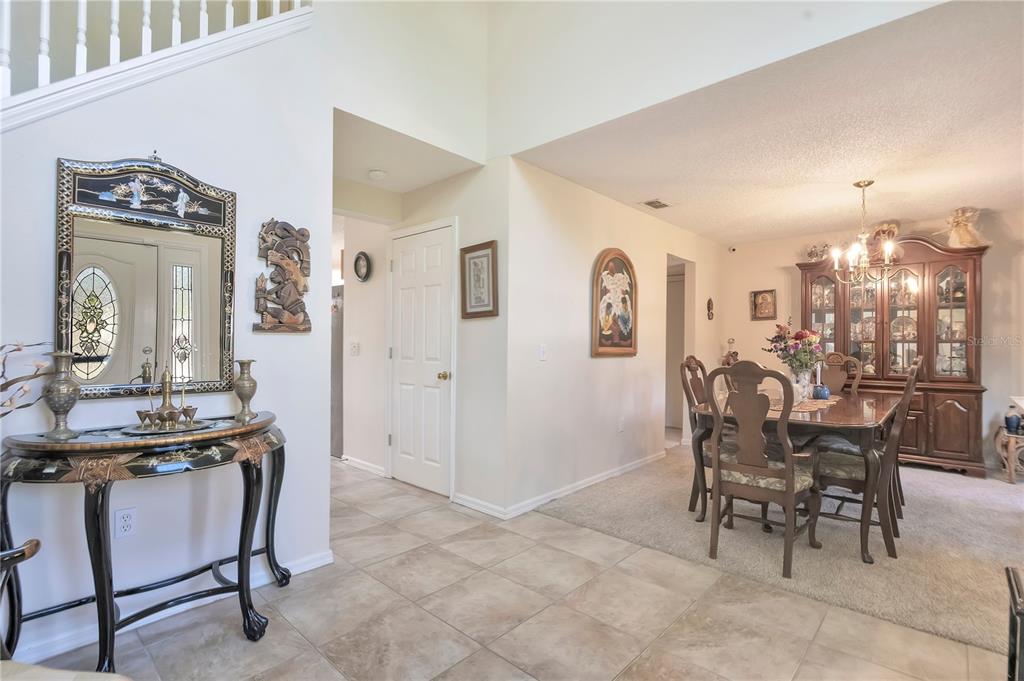 An entryway with tile flooring leads to a carpeted dining room with a wooden hutch — 16012 HORIZON COURT, CLERMONT, FL