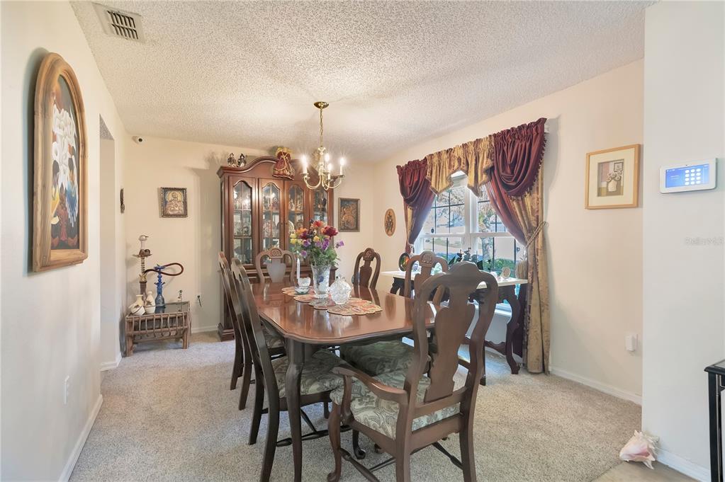 A formal dining room features a wooden table and chairs, a china cabinet, and carpet — 16012 HORIZON COURT, CLERMONT, FL