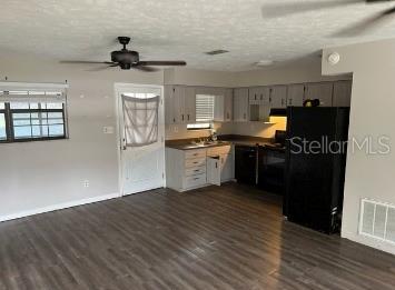 An open-concept kitchen and living area featuring wood-look flooring and a ceiling fan — 12450 SE 99TH AVENUE, BELLEVIEW, FL