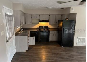 A kitchen features light wood cabinets, black appliances, dark countertops, and wood-look flooring — 12450 SE 99TH AVENUE, BELLEVIEW, FL