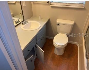 A bathroom with a light gray vanity, a white sink, and a white toilet — 12450 SE 99TH AVENUE, BELLEVIEW, FL