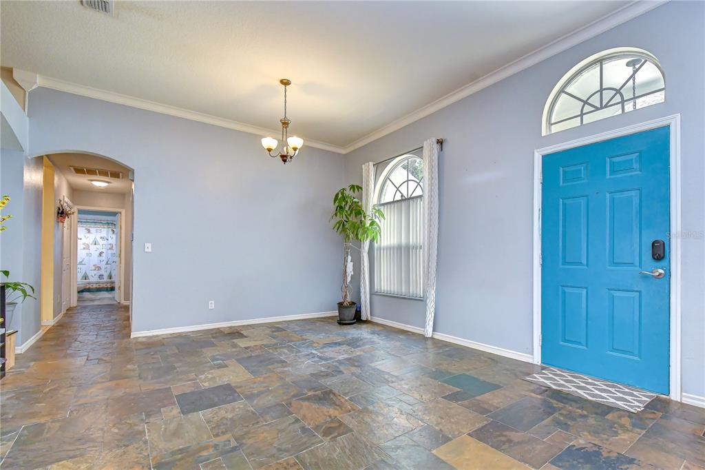 An entryway with slate tile flooring, a bright blue front door, and a chandelier — 4822 PORTOBELLO CIRCLE, VALRICO, FL