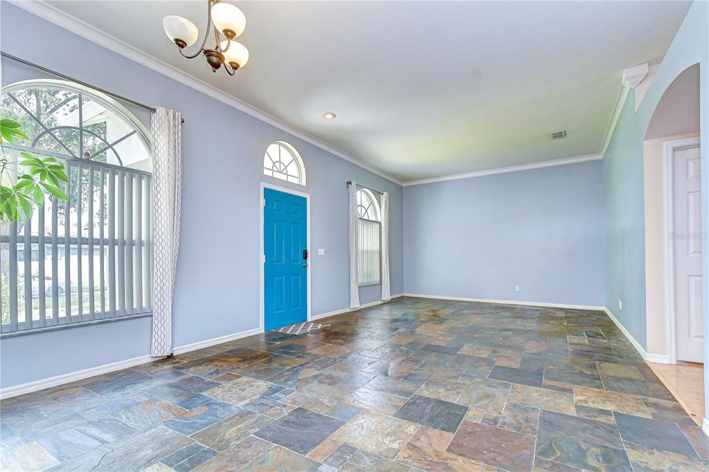 An entryway with light blue walls, a bright blue front door, and slate tile flooring — 4822 PORTOBELLO CIRCLE, VALRICO, FL