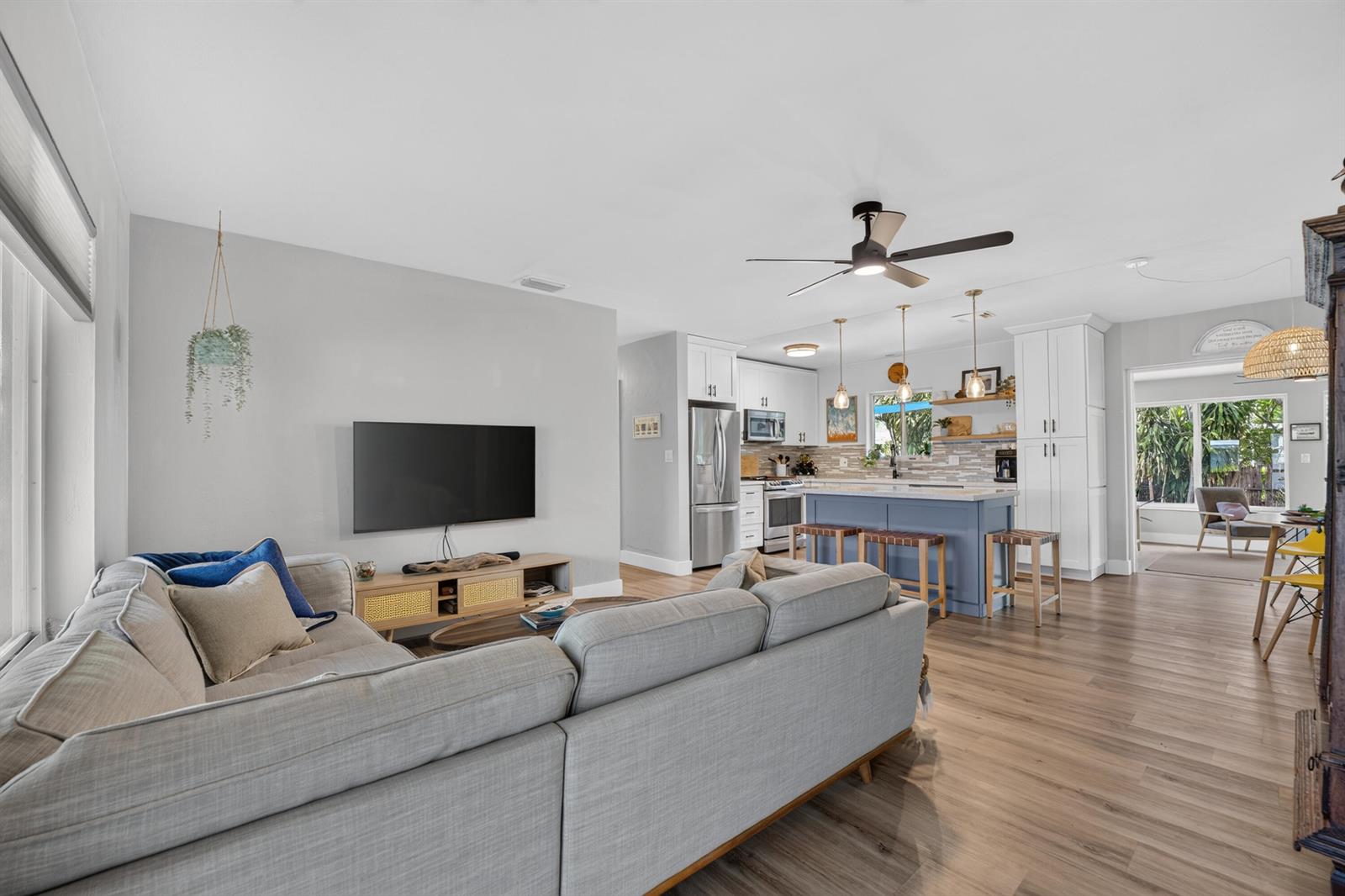 A living room with a gray sectional sofa opens into a kitchen with a blue island — 510 NE 8th Street, Pompano Beach FL 33060, POMPANO BEACH, FL