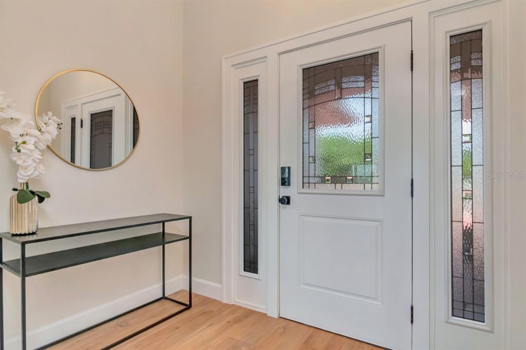 An entryway features a white front door with stained glass panels, a console table, and mirror — 7025 BOCA CIEGA DRIVE, ST PETE BEACH, FL