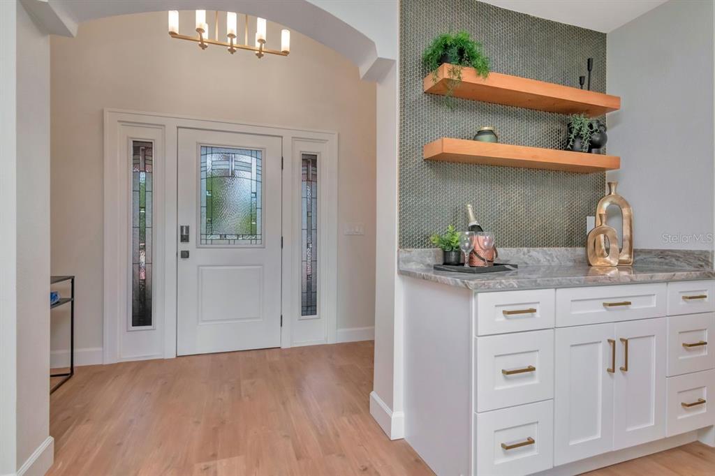An entryway features a white front door, wood flooring, and a built-in wet bar area — 7025 BOCA CIEGA DRIVE, ST PETE BEACH, FL