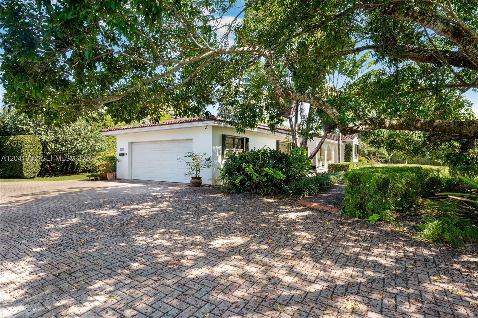 A white house with a brick driveway and large trees in the front yard — 8480 SW 66th St # 0, Miami FL 33143, MIAMI, FL