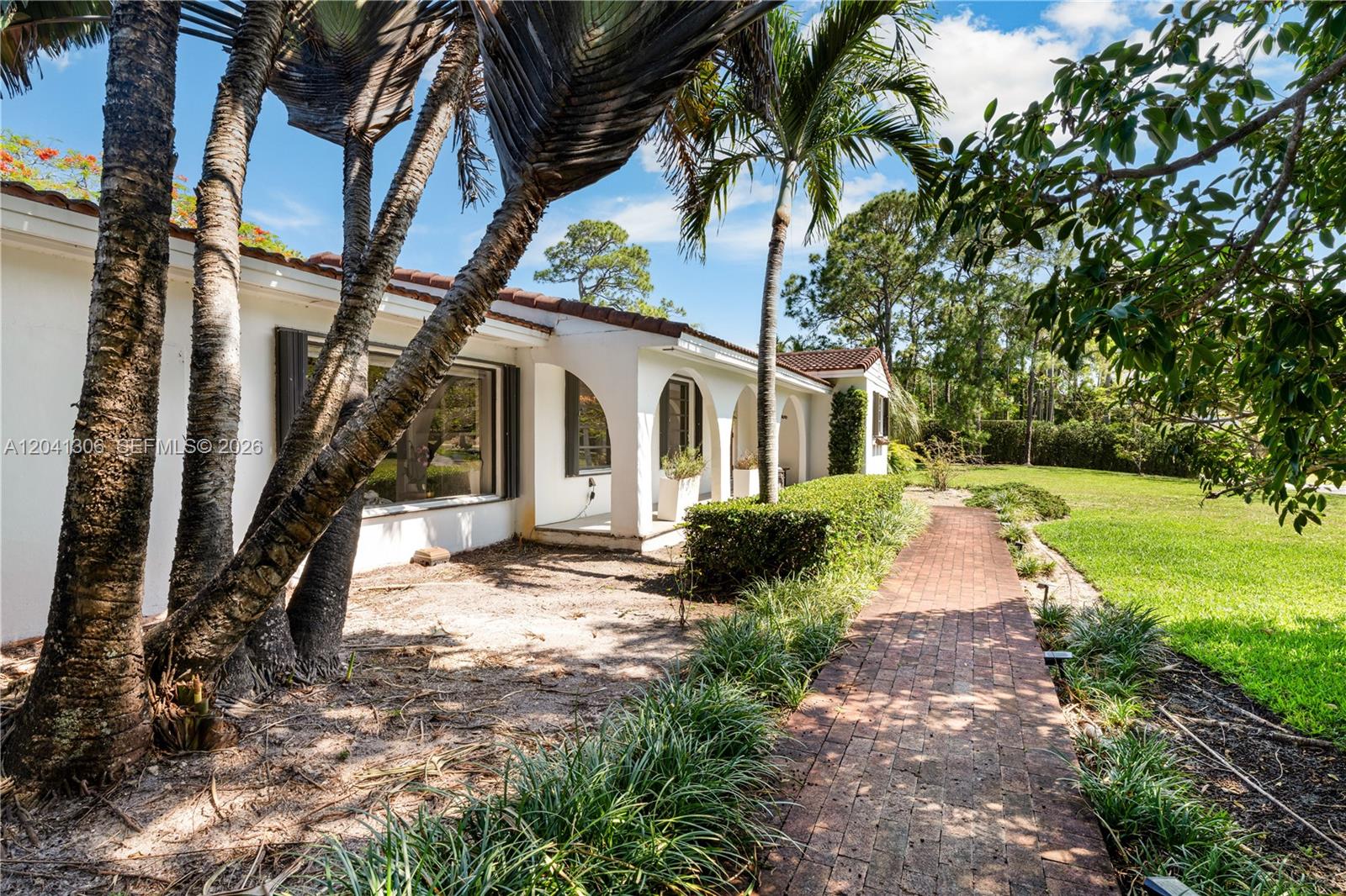 A brick walkway leads along the exterior of a white house with arched entryways — 8480 SW 66th St # 0, Miami FL 33143, MIAMI, FL