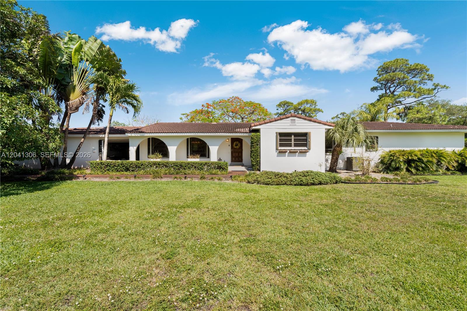 A single-story white house with arched entryways and a brown tile roof sits on grass — 8480 SW 66th St # 0, Miami FL 33143, MIAMI, FL