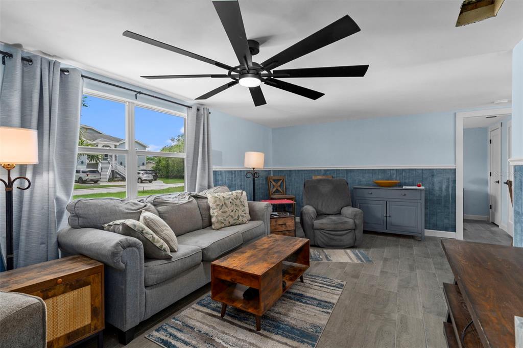 A living room features a gray sofa, wood coffee table, ceiling fan, and blue wainscoting — 5549 QUIST DRIVE, PORT RICHEY, FL